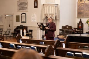 Bishop Susan stands delivering her lecture at the front of St. Mark's sanctuary.